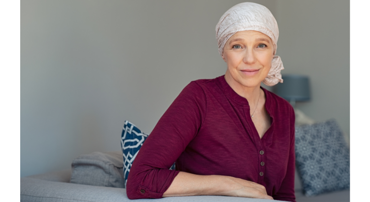 A caucasian woman wearing a red blouse and white headscarf looking gravely into the camera, against a neutral grey background