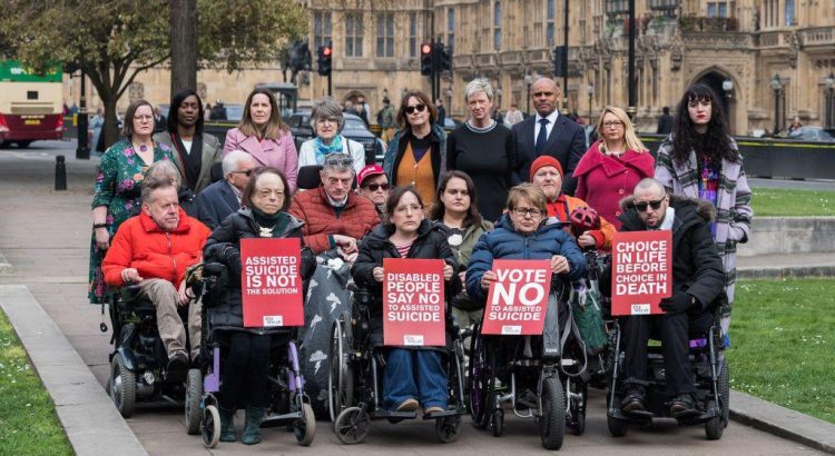 A group of disabled people protesting outside the Houses of Parliament against the Assisted Dying Bill