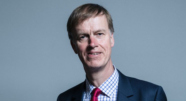 A portrait image of Sir Stephen Timms MP. He is a older white male with short hair, wearing a blue suit and red tie.